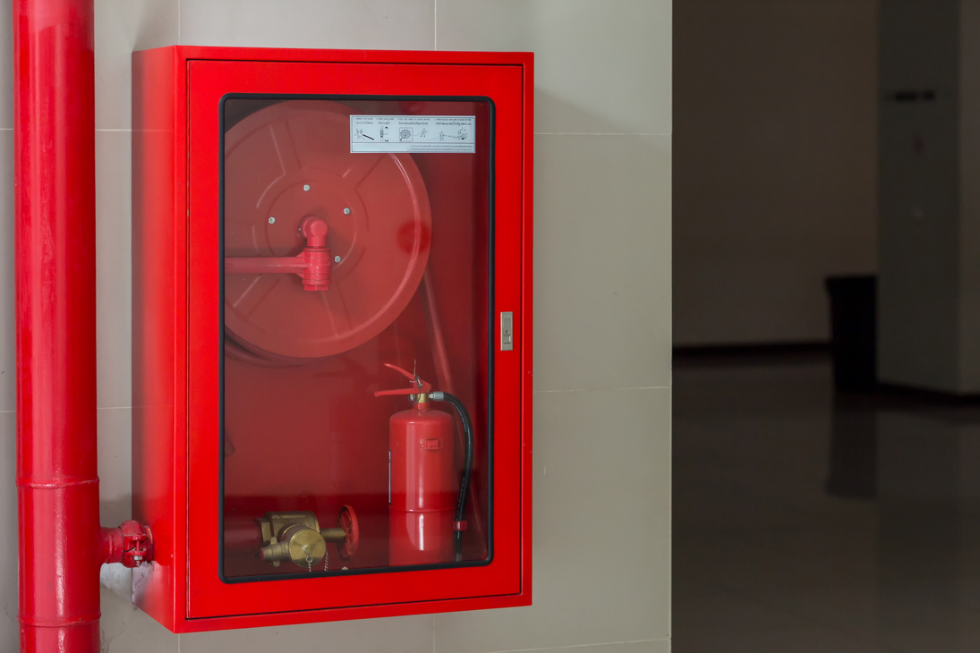 Hydrant with water hoses and fire extinguish equipment. Fire safety equipment in the red box on wall cement .