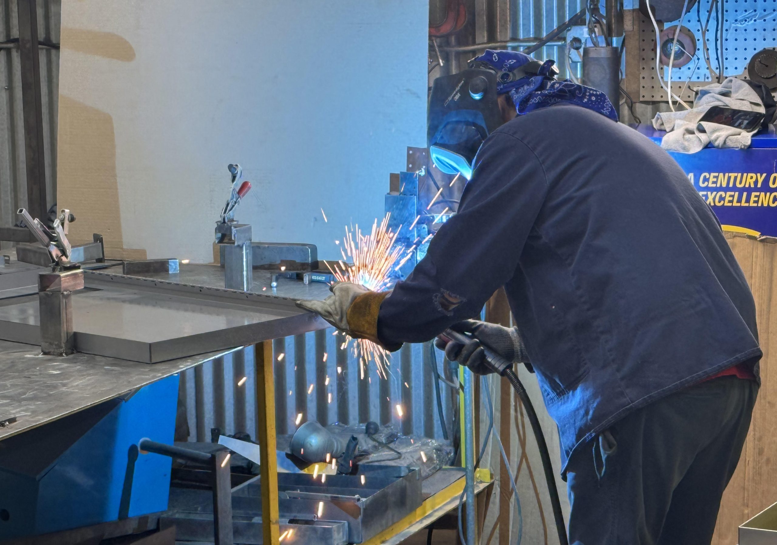 Welder fabricating custom sheet metal at K-Display’s Chicago facility — single-source metal fabrication, powder coating, and assembly